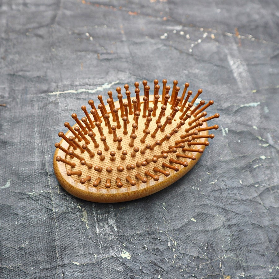 A close-up of the travel brush's soft bristles and scalp massage function.